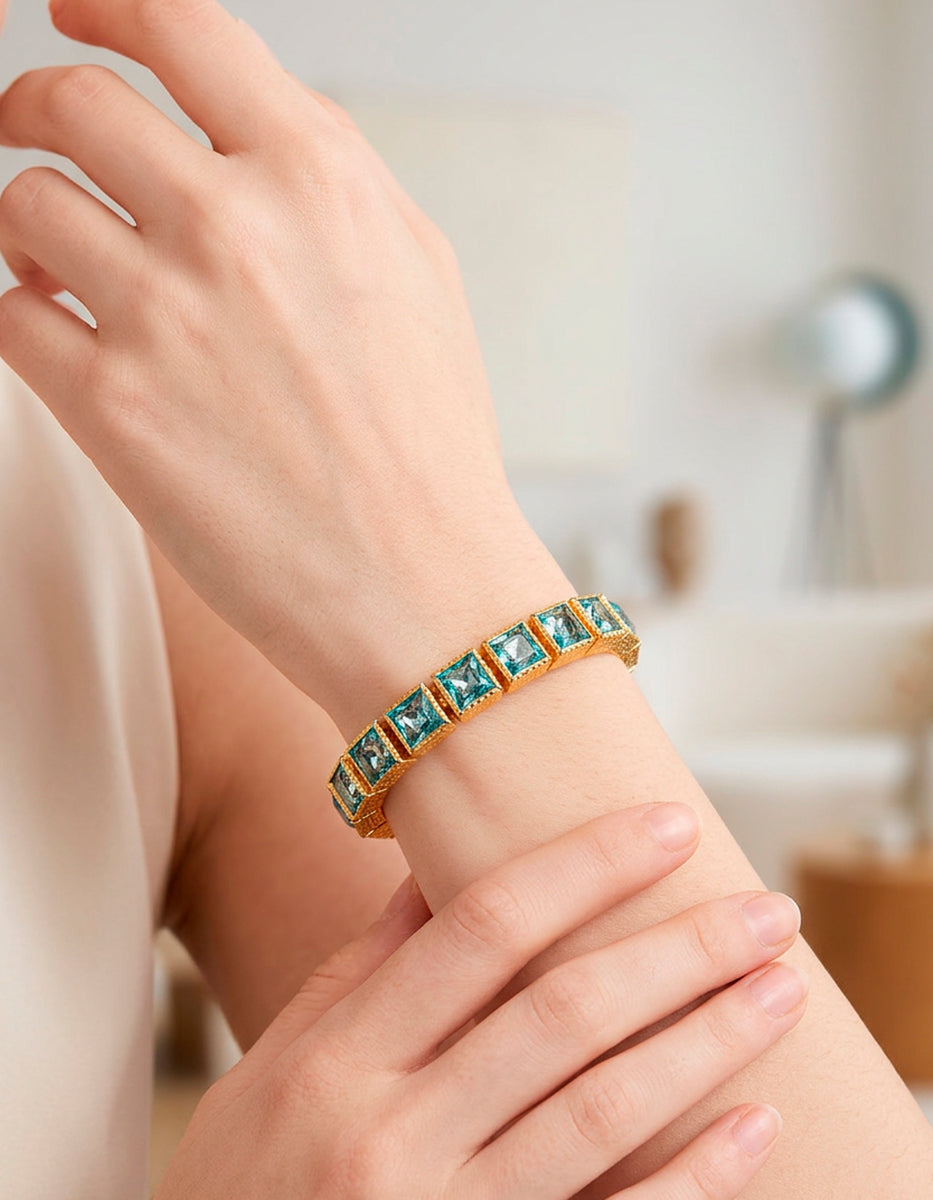 Brazalete de bronce con baño de oro 22k y topacios azules y blancos en corte princesa