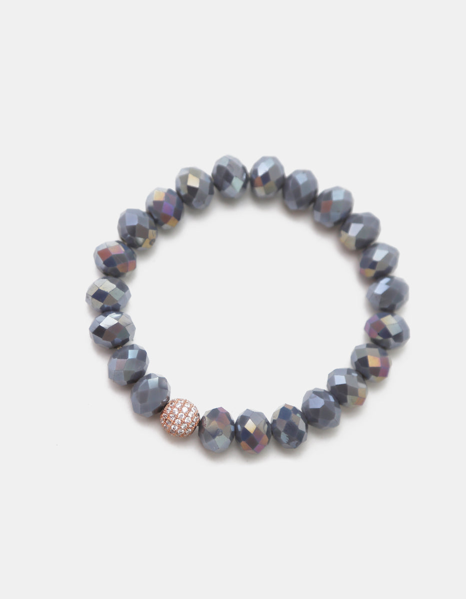 Pulsera de cristal gris metálico con dije esférico en bronce con baño de platino y circonias