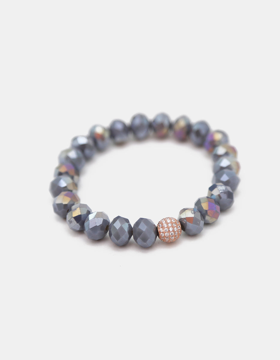 Pulsera de cristal gris metálico con dije esférico en bronce con baño de platino y circonias