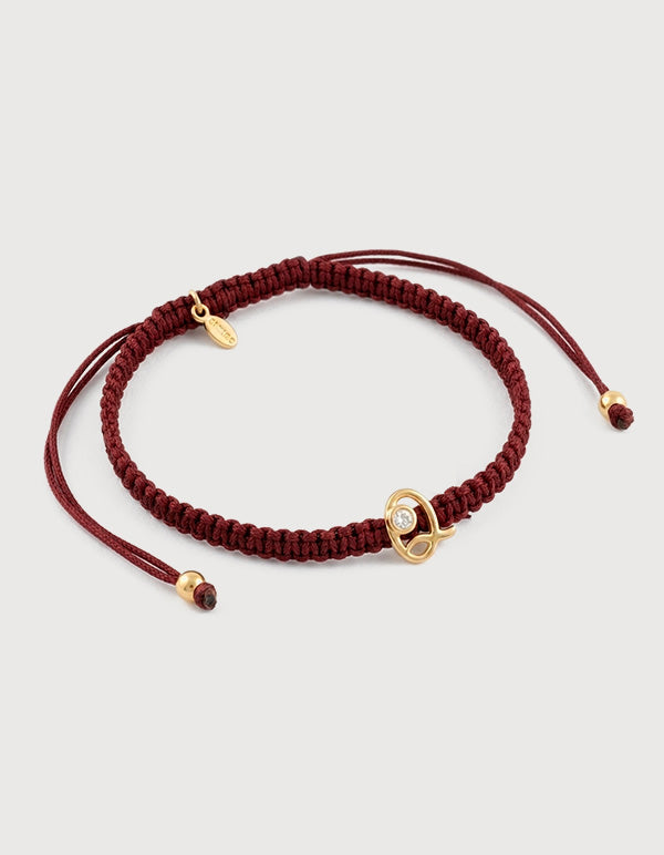 Pulsera con dije de metal noble con baño vermeil 22k con la letra Q y cordón trenzado