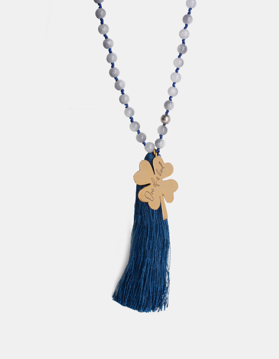 Collar de cuentas azul con dije trébol en bronce baño oro de 22kt y pompon