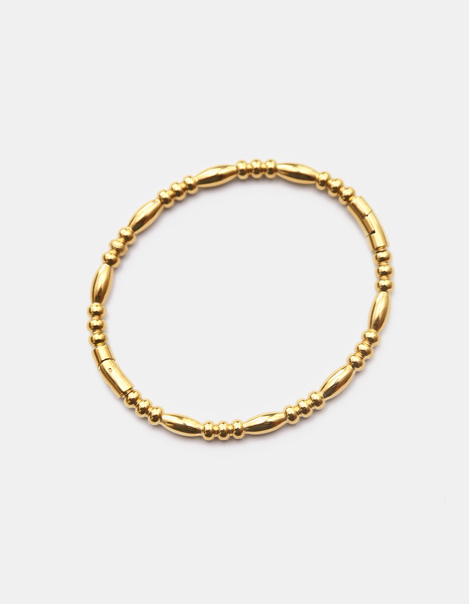 Brazalete rígido de bronce en baño de oro 22 kt con secuencia de balines y secciones de oliva