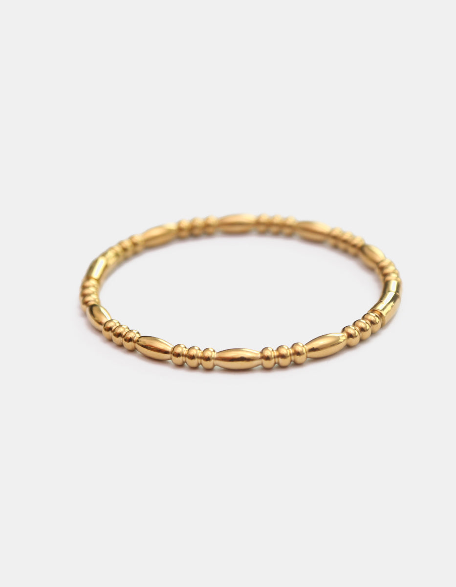 Brazalete rígido de bronce en baño de oro 22 kt con secuencia de balines y secciones de oliva